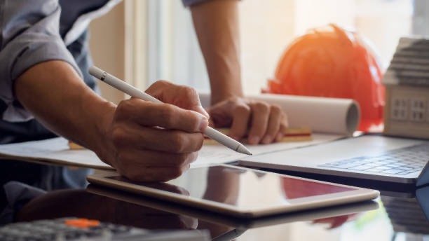 Étude d’un projet de rénovation sur tablette, à côté de plans et d’un casque de chantier